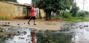 A man crosses a street flooded by sewage in the township of Dzivaresekwa in Harare