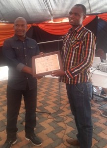 Paddy Dzamara receives the award from CIZC's Mfundo Mlilo
