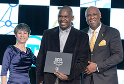 Issaya Mutombo (centre) is presented with the award by Dr. Kendall T.Harris (right) and Duy-Loan Le