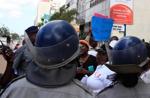 Anti-riot police clash with the protestors outside the Kuwait embassy in central Harare