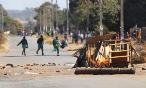 Schoolchildren run past a burning barricade in Harare. Photograph: Tsvangirayi Mukwazhi/AP