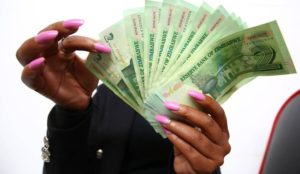 A woman holding the new two dollar bond notes in Harare, Zimbabwe, 28 November 2016. EPA/AARON UFUMELI